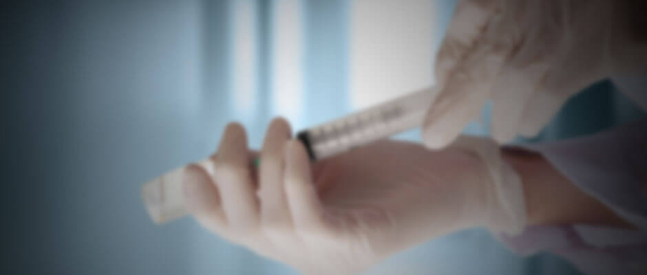 Hands of medical professional with gloves on holding a syringe for a vaccine